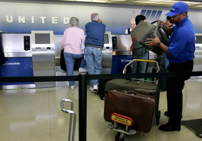 Los Angeles, CA.  A contracted baggage handler, who declined to give his name, loads luggage onto