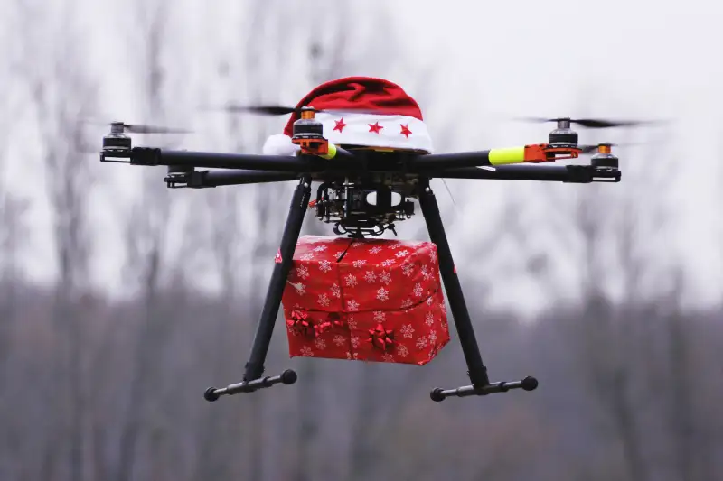 Drone With Santa Hat Carrying Christmas Present Against Sky