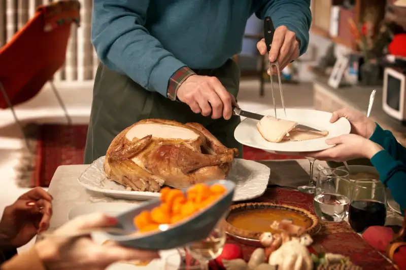 Man serving turkey at dining room table, mid section