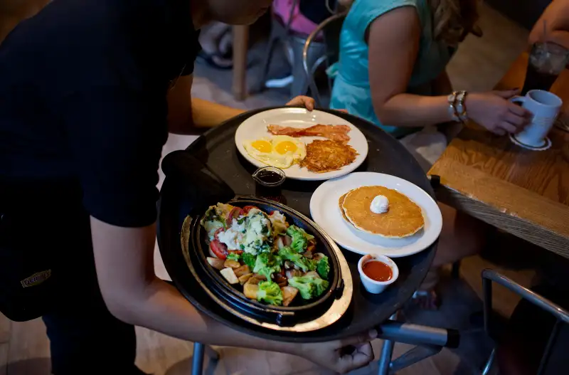 A waitress delivers a tray of food to customers at the Denny's