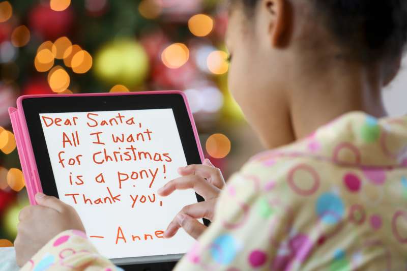 Black girl writing letter to Santa on digital tablet