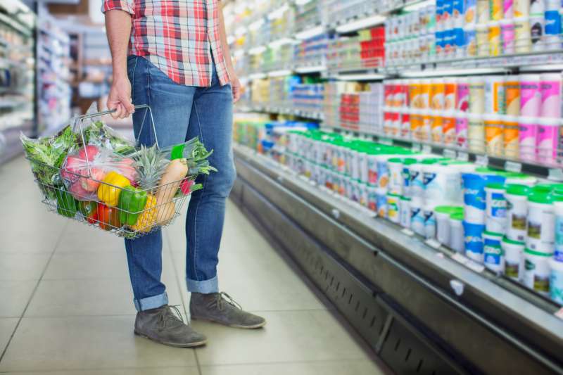 Man carrying full shopping basket in grocery store