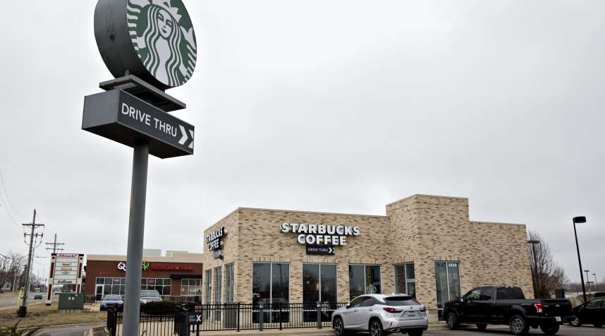 Vehicles sit parked outside of a Starbucks Corp. coffee shop in Peoria, Illinois, U.S., on Wednesday, Jan. 25, 2017.