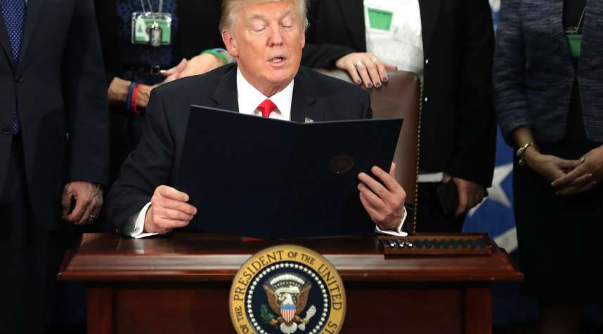 U.S. President Donald Trump, center, reads from an executive order at the Department of Homeland Security (DHS) in Washington, D.C. U.S., on Wednesday, Jan. 25, 2017. Trump acted on two of the most fundamental -- and controversial -- elements of his presidential campaign, building a wall on the border with Mexico and greatly tightening restrictions on who can enter the U.S.