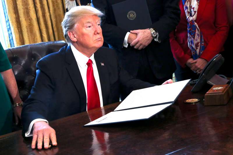 U.S. President Donald Trump signs Executive Orders in the Oval Office of the White House, including an order to review the Dodd-Frank Wall Street to roll back financial regulations of the Obama era February 3, 2017 in Washington, DC.