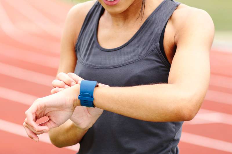 Young woman on running track, checking watch