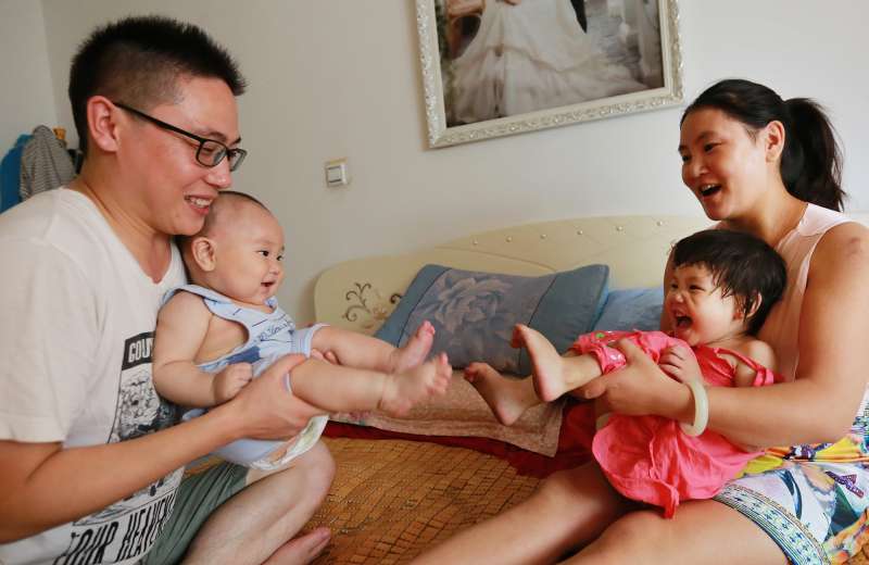 A Chinese couple plays with their two children at home in Xi'an city, northwest China's Shaanxi province, on July 27 2016.