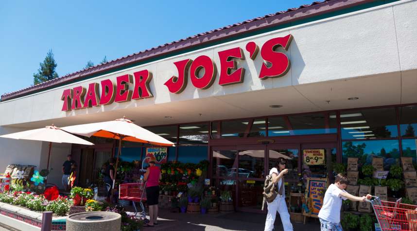 Shoppers going in and out of Trader Joe's grocery store on a sunny summer day.