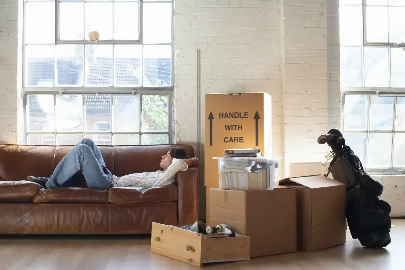 Young man lying down on sofa wearing headphones