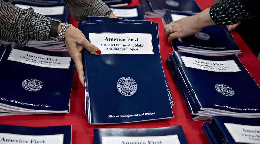 Employees arrange copies of U.S. President Donald Trump's fiscal 2018 budget request, America First: A Budget Blueprint to Make America Great Again, at the Government Printing Office (GPO) library in Washington, D.C., U.S., on Thursday, March 16, 2017. President Donald Trump is proposing historically deep budget cuts that would touch almost every federal agency and program and dramatically reorder government priorities to boost defense and security spending.