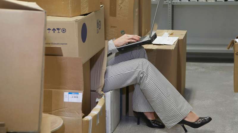 woman on laptop hiding in storage room