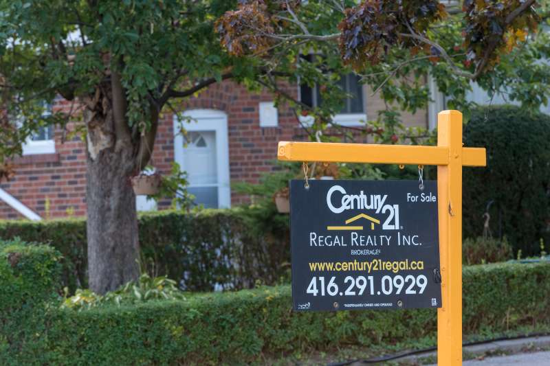 A Century 21 realtor board with a for-sale sign hung outside a residential house in Toronto.