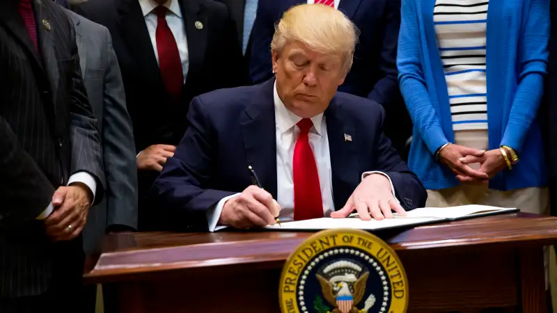 President Donald Trump signs an executive order in the Roosevelt Room at The White House on April 28, 2017 in Washington, D.C.