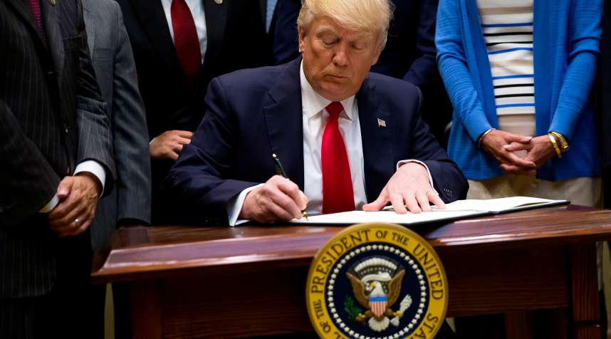 President Donald Trump signs an executive order in the Roosevelt Room at The White House on April 28, 2017 in Washington, D.C.