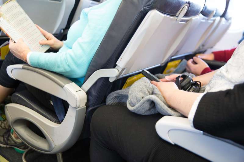 Passengers seated on an airplane are cramped in their seats
