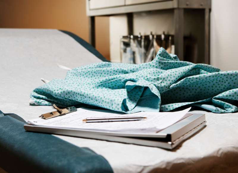Medical chart and examination gown on table in exam room