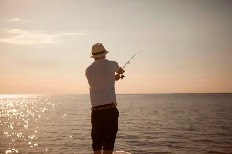 Man fishing in still ocean