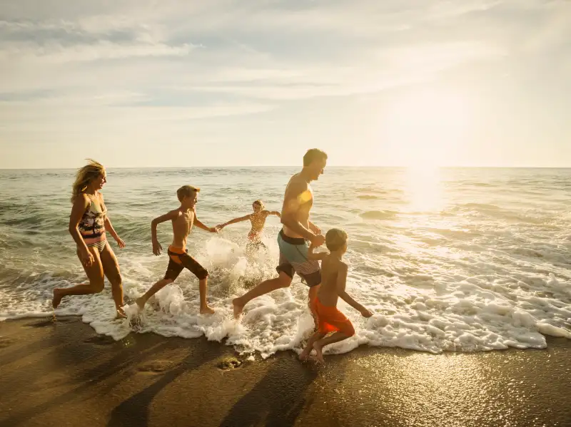 USA, California, Laguna Beach, Family with three children (6-7, 10-11, 14-15) running on beach