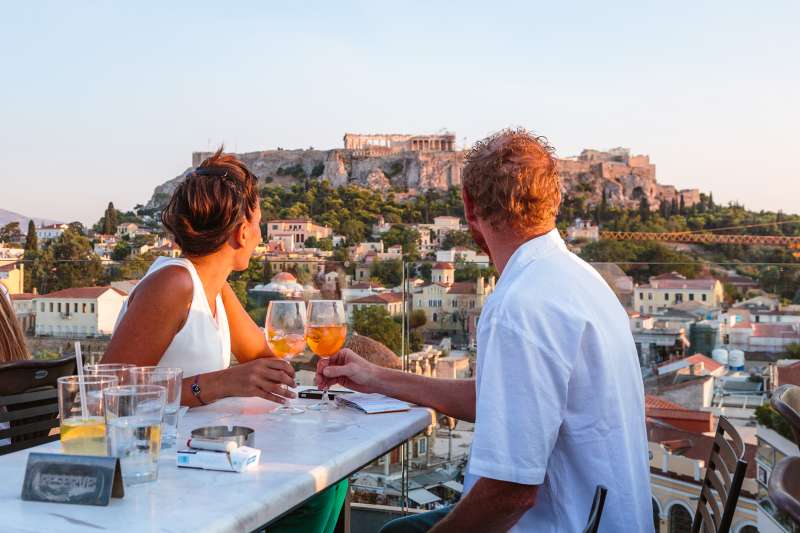 Couple drinking and enjoying the view of the Acropolis at sunset, Athens, Greece