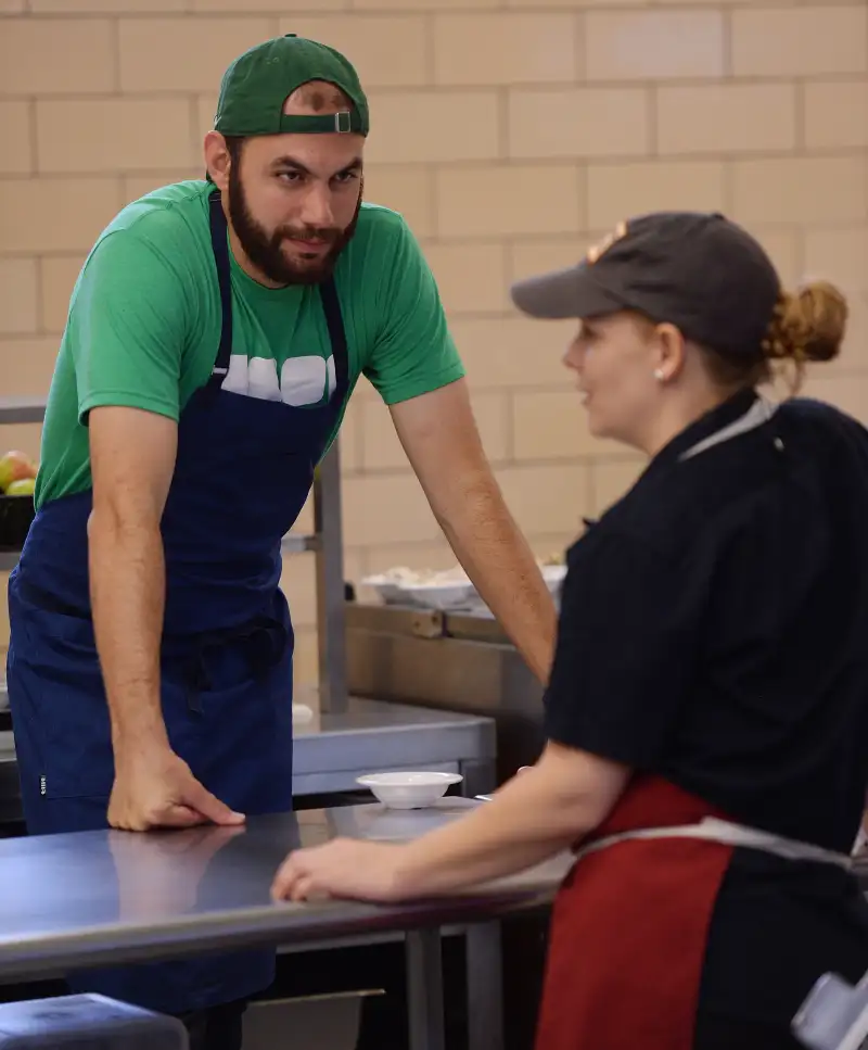 In this Sept. 23, 2016 photo, chef Daniel Giusti, left, chats with chef April Kindt between lunch waves at Bennie Dover Jackson Middle School in New London, Conn. The New London school district is in the midst of what's been called a food revolution following the hiring of two professional chefs. The Day reports students at Bennie Dover Jackson Middle School and New London High School are having meals that are something they say they've never seen the likes of in a school cafeteria.