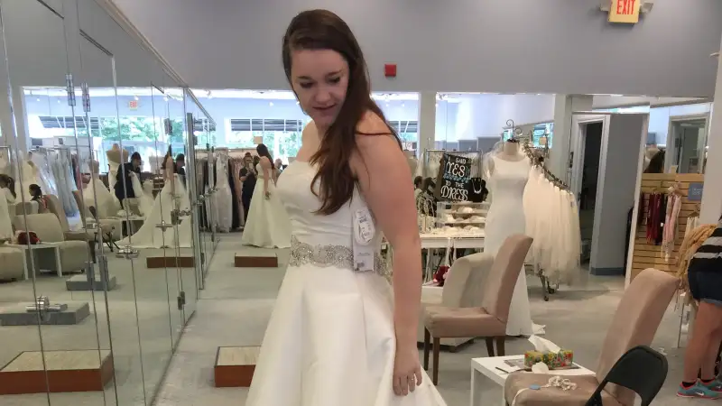 Mary-Catherine Donaghy stands in the dress she bought from Alfred Angelo. She says she has not heard from the company and believes she will have to buy a new dress.