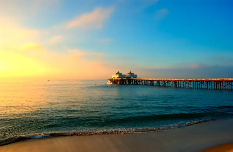 A long pier over an ocean and beach