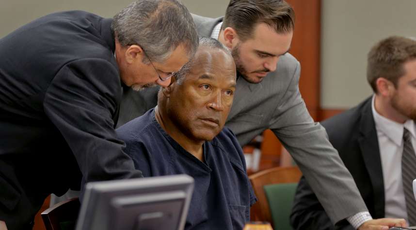 O.J. Simpson (C) talks with defense attorneys Ozzie Fumo (L) and Dustin Marcello during an evidentiary hearing for O.J. Simpson in Clark County District Court in Clark County District Court May 16, 2013 in Las Vegas, Nevada.