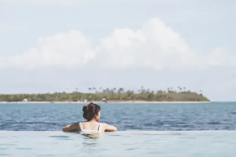 Woman In Swimming Pool By Sea Against Sky