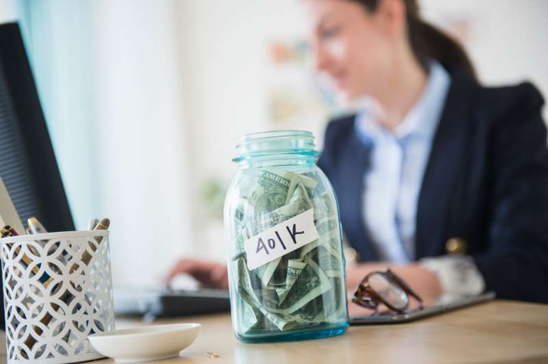 Woman in office with jar full of money on her desk