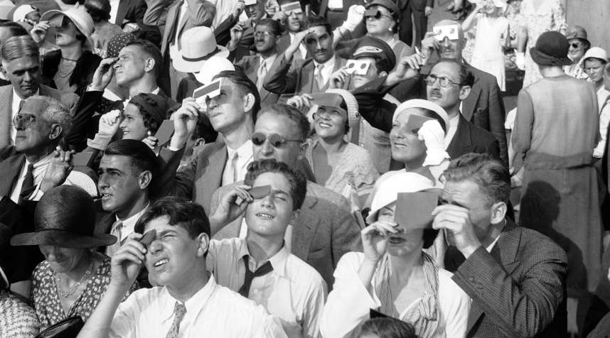 On Aug. 31,1932, eclipse watchers squint through protective film as they view a partial eclipse of the sun from the top deck of New York's Empire State Building.