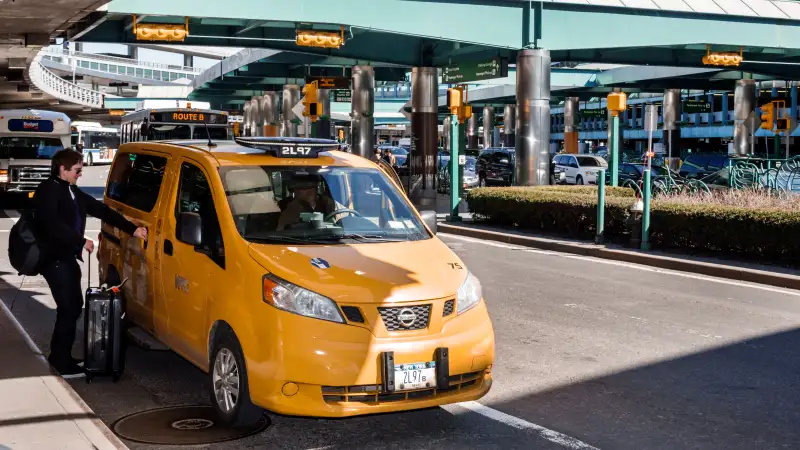 A taxi picking up a passenger outside LaGuardia Airport.