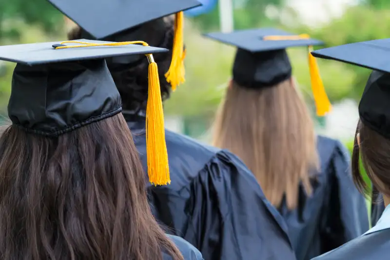 High school or college graduates walking across lawn