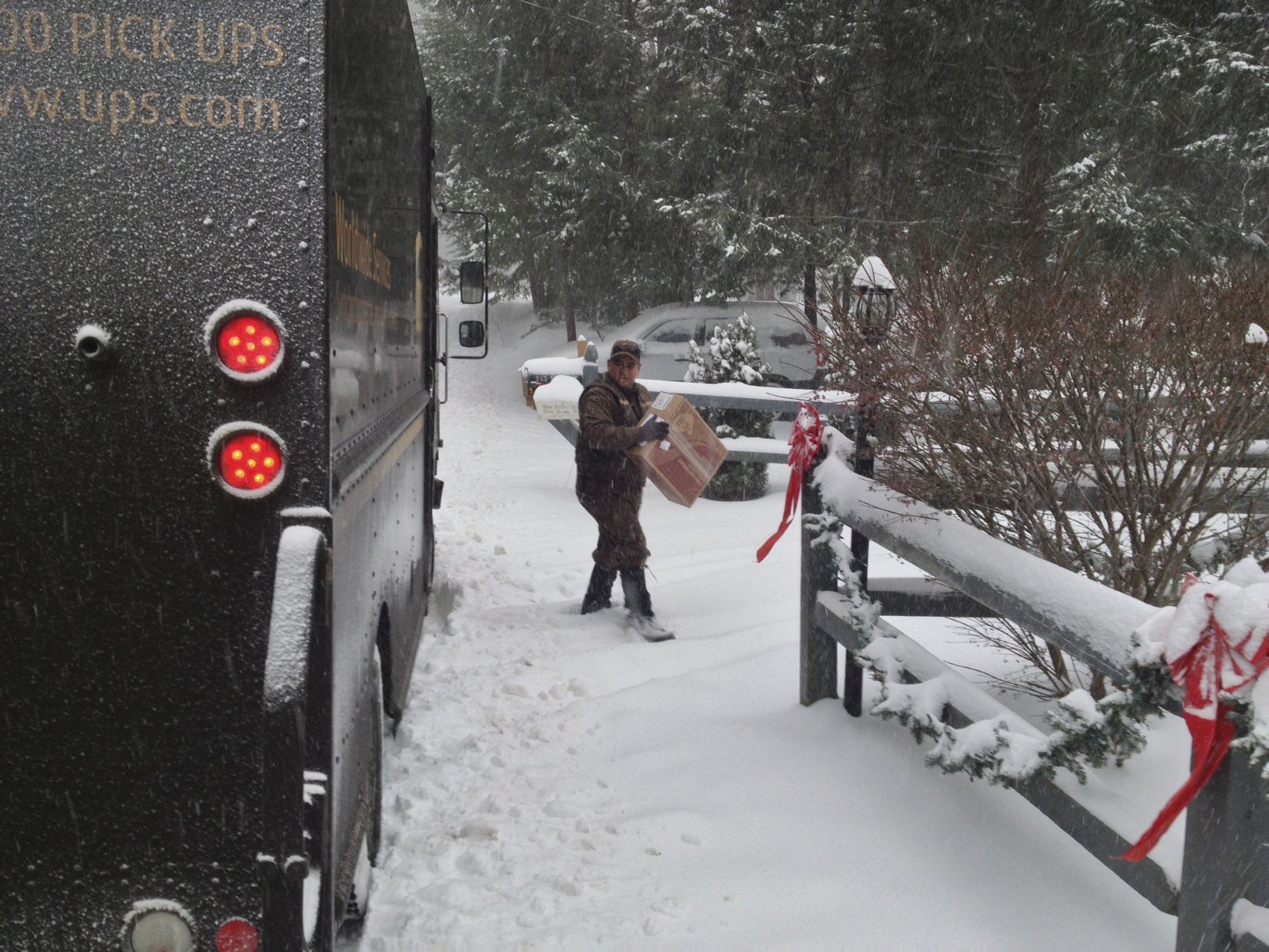 John Cortes, a driver for UPS, delivers a package to a Windham home as the snow deepens Thursday, De