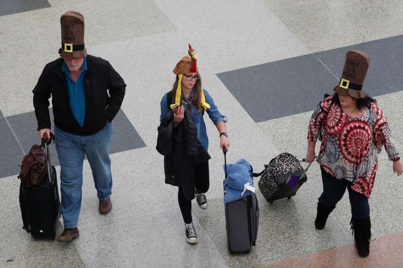 From left, Jack, Nikki  and Rae Forbes of Asheville, N.C., wear hats to fit the holiday as they head through the terminal after arriving at Denver International Airport early Wednesday, Nov. 23, 2016, in Denver. Travelers are criss-crossing the country Wednesday, clogging airport terminals in a rush to reach their Thanksgiving Day destinations.