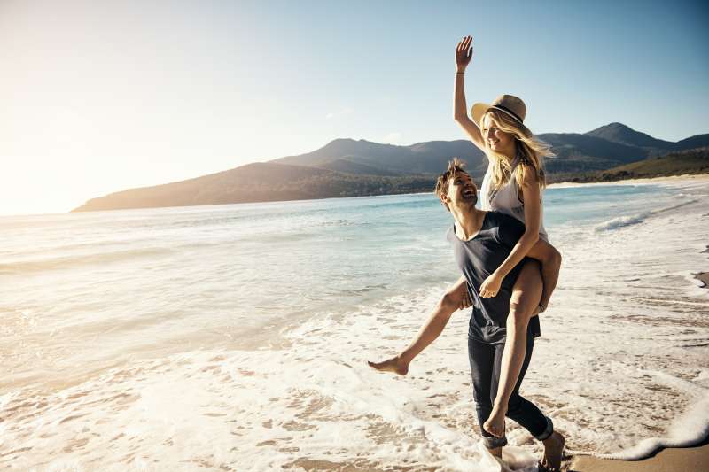 Shot of a young couple enjoying a piggyback ride at the beach