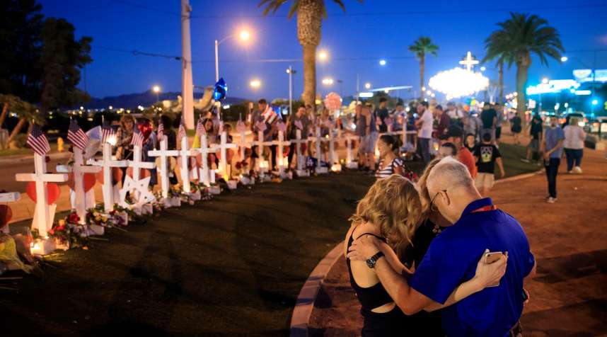 A small group prays at a makeshift memorial with 58 white crosses, one for each victim, on the south end of the Las Vegas Strip, October 6, 2017 in Las Vegas, Nevada. On October 1, Stephen Paddock opened fire on the crowd at the Route 91 Harvest country music festival, killing 58 people and injuring more than 450. The massacre is one of the deadliest mass shooting events in U.S. history.