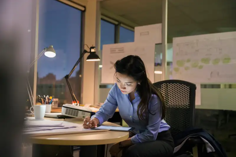 Businesswoman with digital tablet working late in office