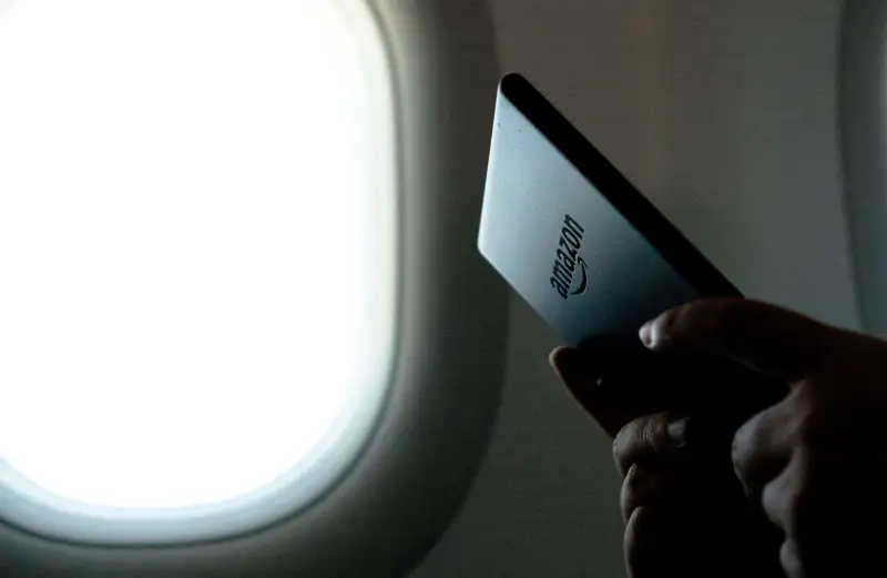 A person reads a kindle ebook on an airplane.  Amazon