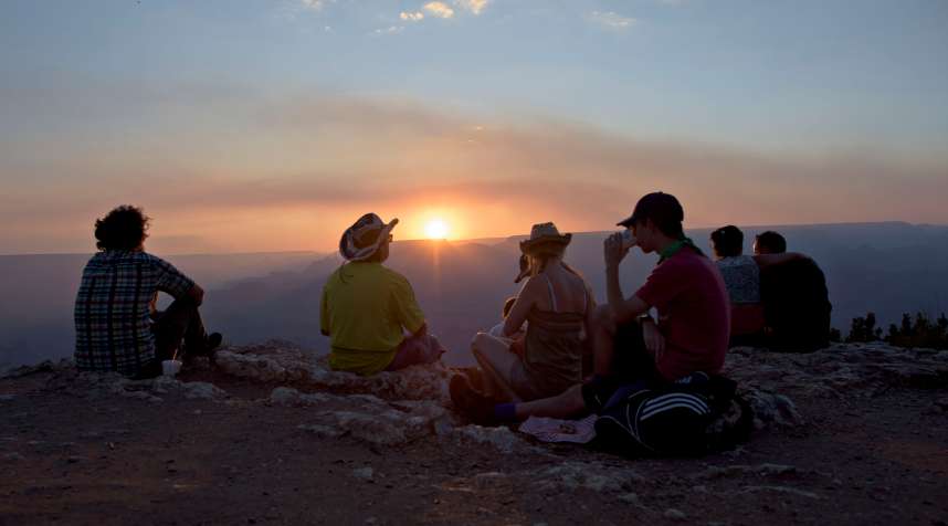 Visitors watch the sun set over the Grand Canyon at the Desert View observation point in Grand Canyon National Park in Grand Canyon, Arizona, U.S., on Thursday, June 25, 2015. The Grand Canyon has seen a 20 percent increase in visitation through the first quarter of this year, according to a park spokesperson. Photographer: Daniel Acker/Bloomberg via Getty Images