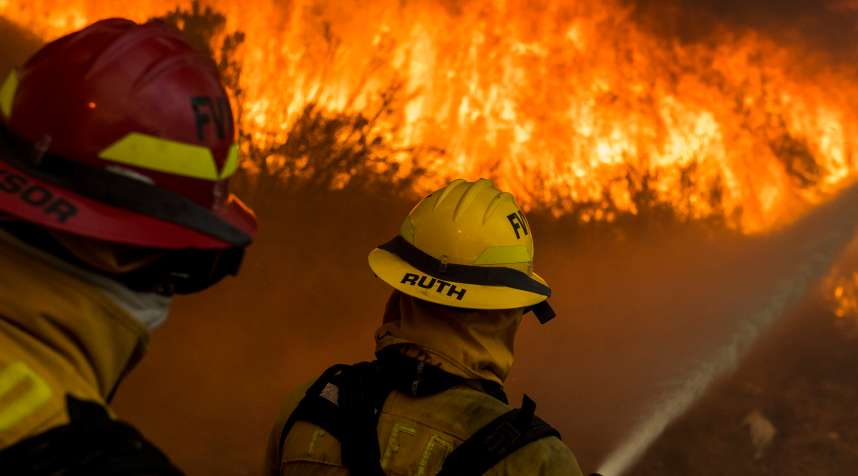 Firefighters from the city of Fountain Valley try to hold back flames from the Canyon Fire 2 along Santiago Canyon Road  on October 9th, 2017 in Anaheim Hills, California.