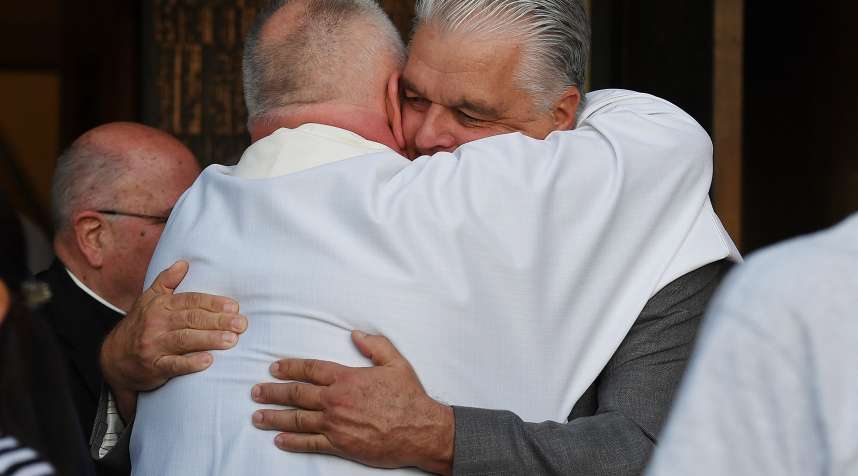 Clark County Commission Chair Steve Sisolak embraces a member of the clergy as he attends a vigil at Guardian Angel Cathedral for the victims of the Route 91 Harvest country music festival shootings on October 2, 2017 in Las Vegas, Nevada.