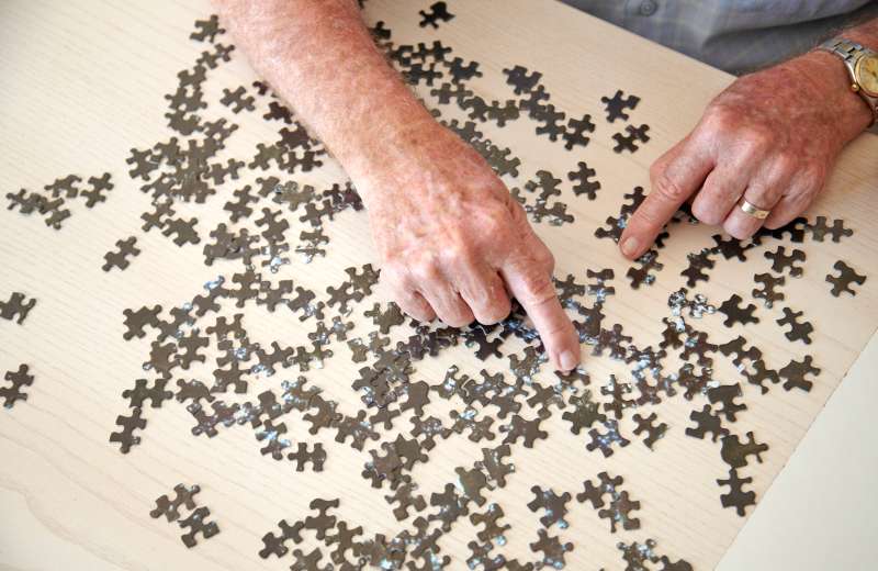 Elderly man doing jigsaw puzzle