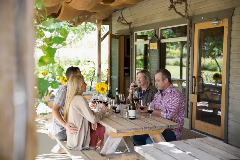 Couples wine tasting drinking red wine on patio at winery tasting room