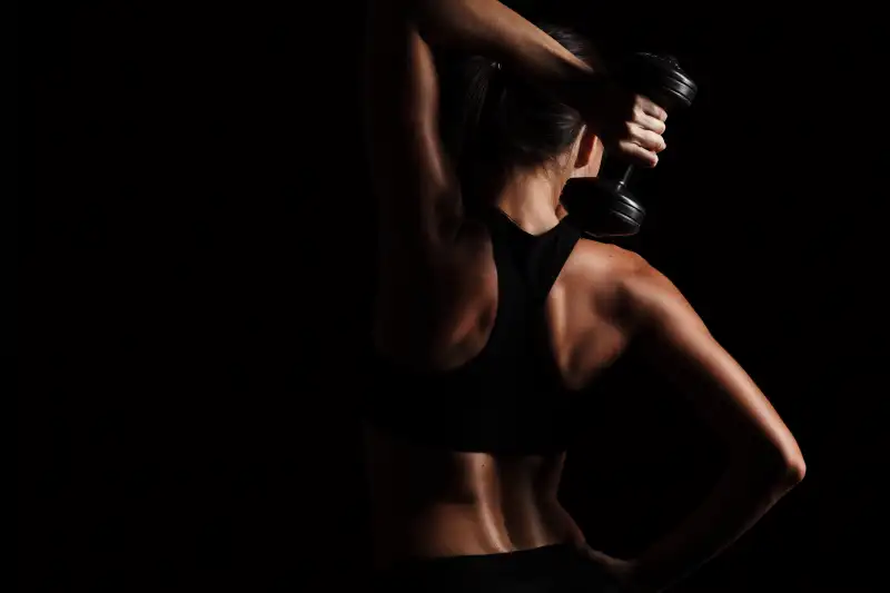 Rare view of female body, exercising with dumbbell