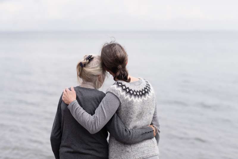 two generations women embracing, looking at sea