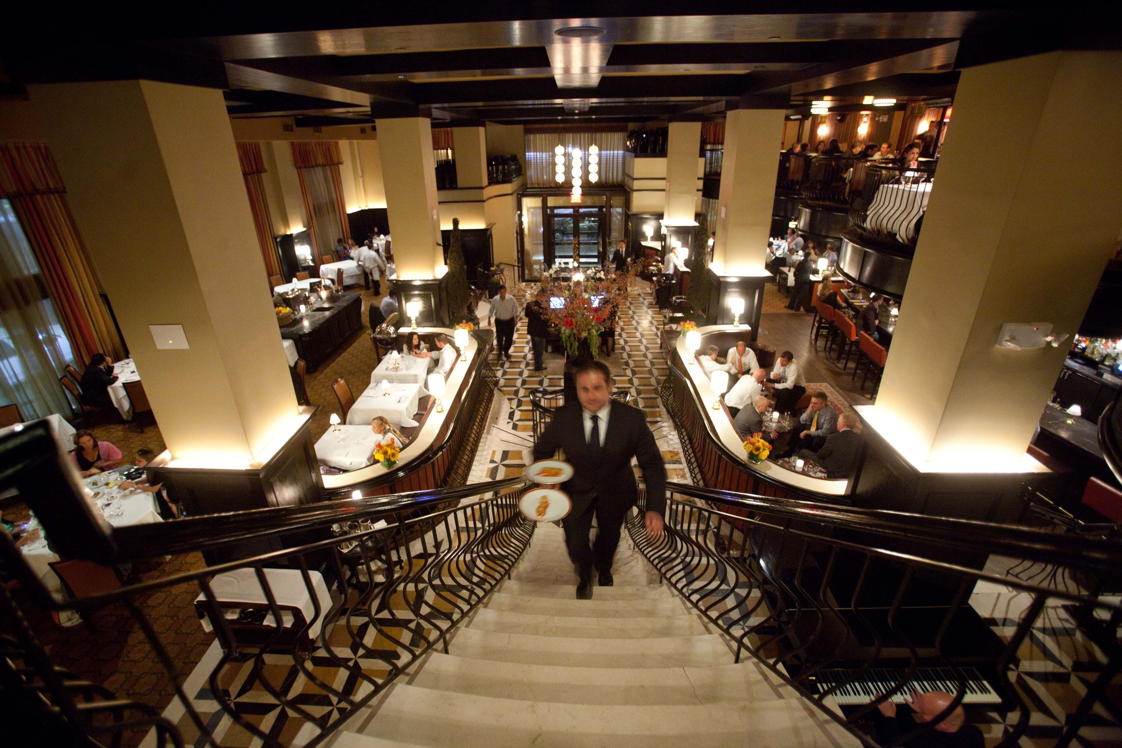 A waiter ascending the staircase to the upper level of Del Posto restaurant in New York.