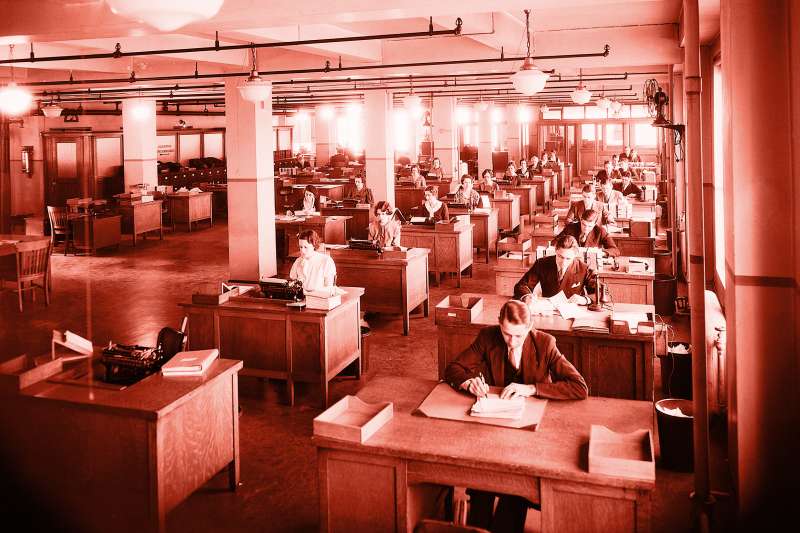 Large business office in New York City, 1930's. There is a row of a dozen men at their desks; next to them are two rows of secretaries.