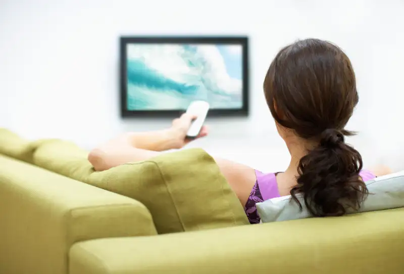 Young woman watching television, rear view