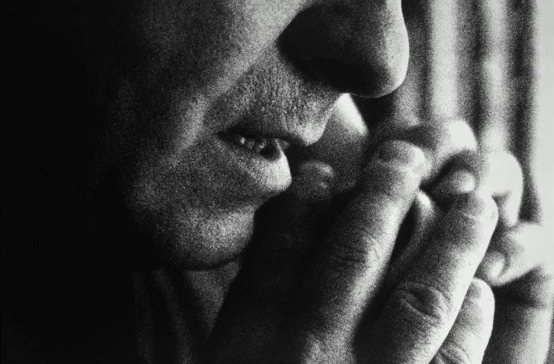 Man using telephone, covering mouthpiece with hand, (grainy B&amp;W)