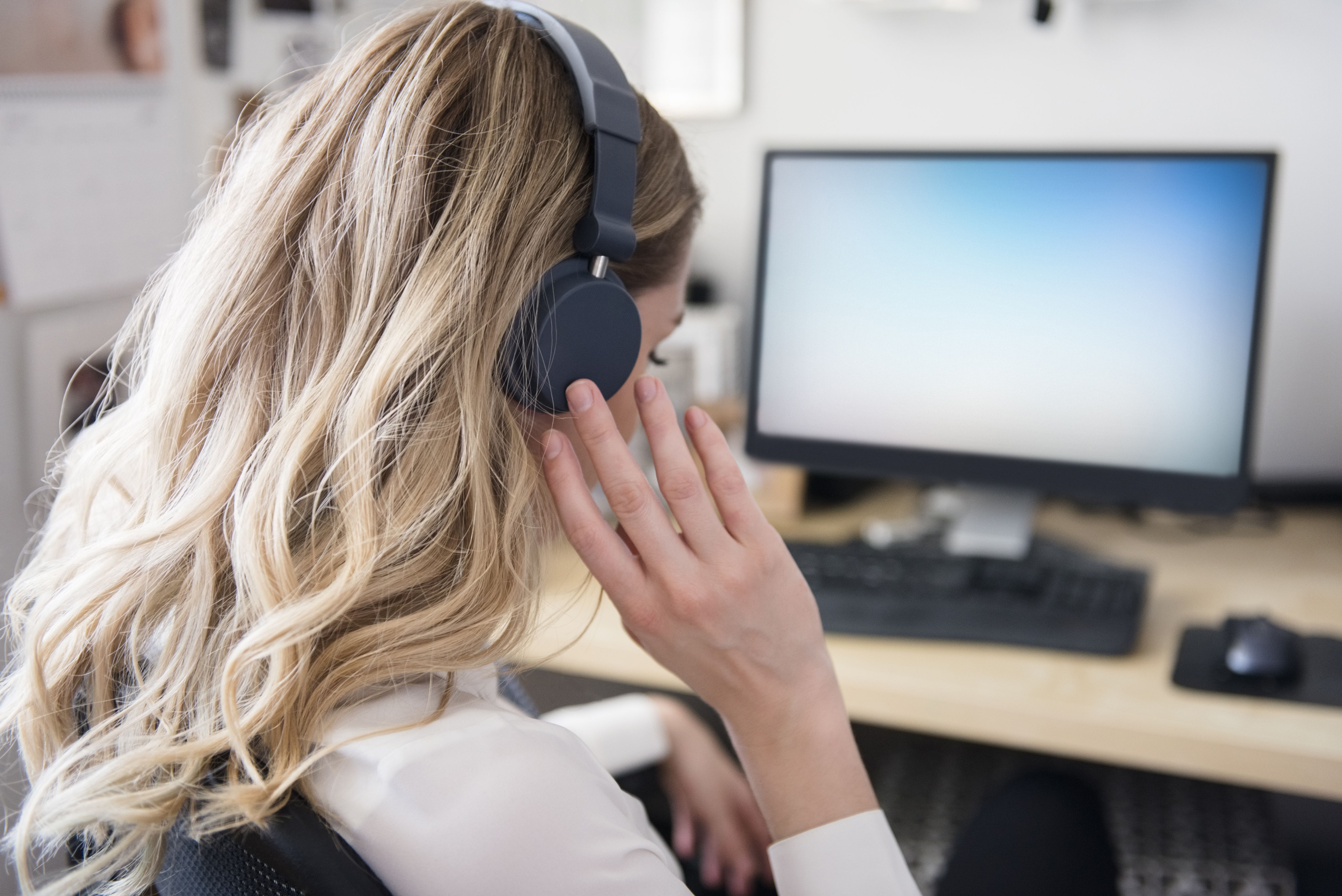 Caucasian woman listening to headphones at computer desk